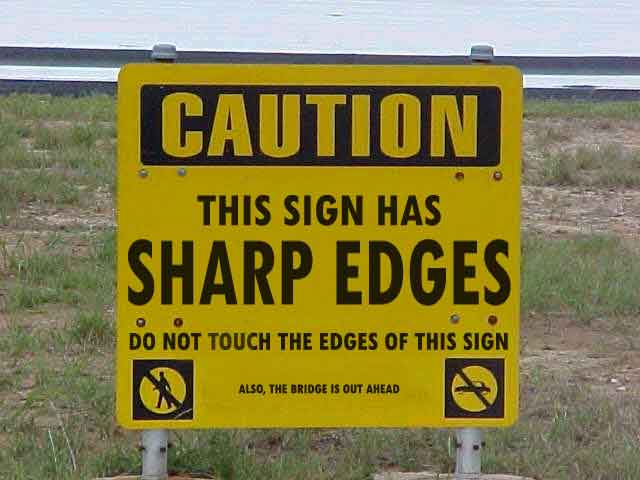 Warning sign - WARNING this sign has sharp edges. Do not touch the edges of this sign. Also, the bridge ahead is out.