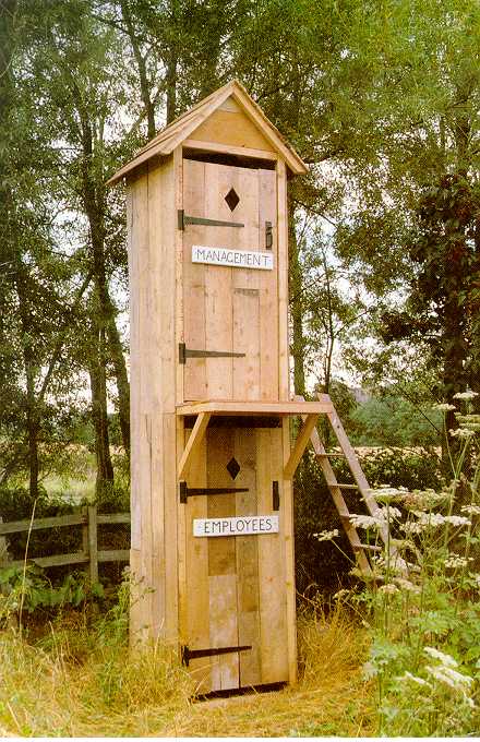 Double-decker outdoor toilet. Bottom door labelled Employees. Top door labelled Management.